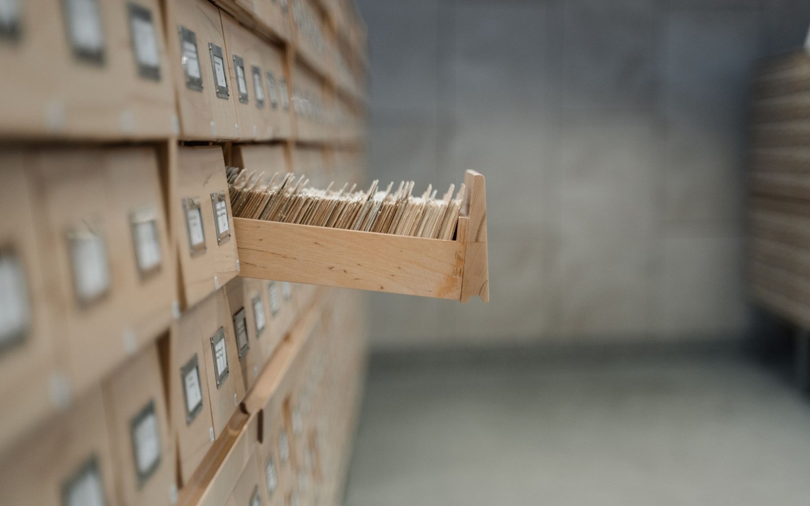 A mailing-list card index open in its drawer, an adult's hand spread across the cards