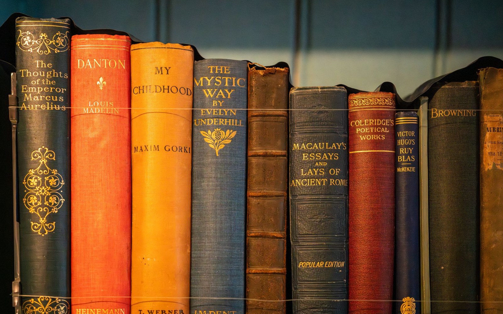 A row of vintage hardcover book spines with gold-lettered titles by classic authors