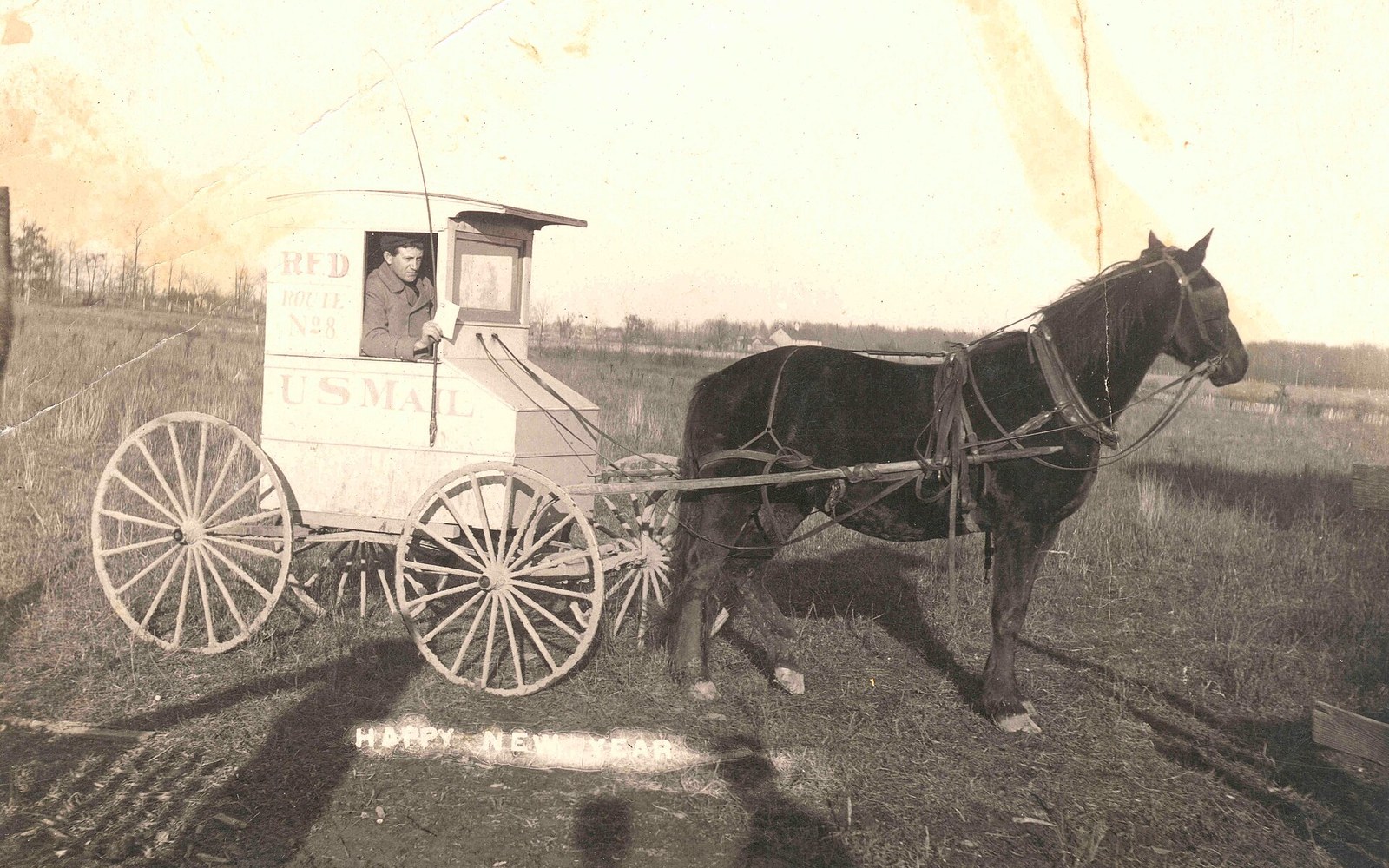 A horse-drawn RFD mail wagon with a carrier sitting inside the enclosed cart