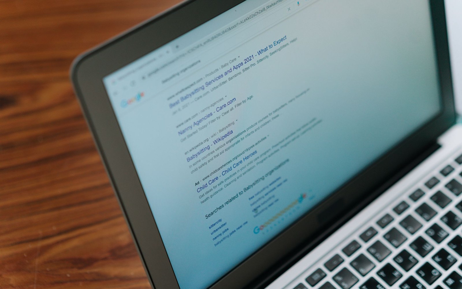 Laptop screen showing search results for babysitting services and nanny agencies